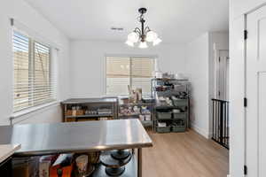 Home office featuring light wood-style floors, suspended lighting, and plenty of natural light