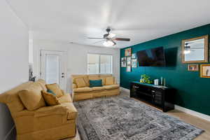 Living area with ceiling fan, light wood finished floors, and a textured ceiling