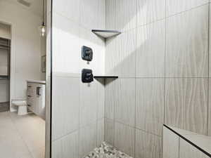 Bathroom with vanity, tiled shower, and light tile patterned floors