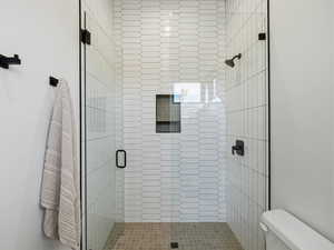 Full bath featuring toilet and a shower stall