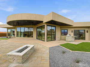 Back of property featuring an outdoor kitchen, ceiling fan, a patio, a fire pit, and stucco siding