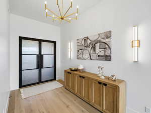 Foyer with light wood-style floors and hanging lights