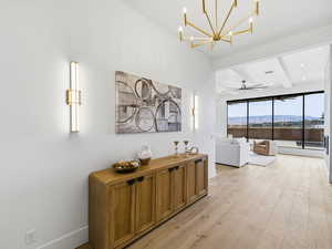 Hallway with hanging lights, light wood-type flooring, a mountain view, and vaulted ceiling with beams