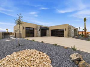 View of front of home featuring stone siding, stucco siding, and driveway