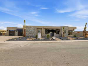 View of front of property with stone siding, stucco siding, concrete driveway, and an attached garage