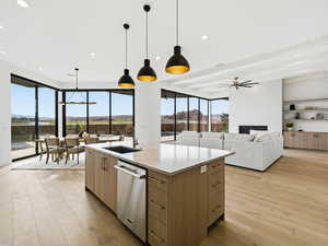 Kitchen featuring light stone countertops, light wood finished floors, open floor plan, stainless steel dishwasher, and modern cabinets