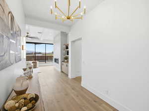 Living room with light wood-style flooring, a chandelier, beam ceiling, and ceiling fan