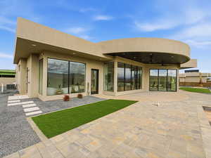 Rear view of property with a ceiling fan, stucco siding, and a patio area