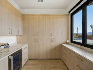 Kitchen featuring light wood finish cabinetry, wine cooler, light wood-type flooring, and modern cabinets