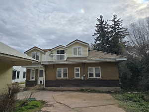 View of front of home with brick siding and a balcony