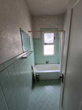 Bathroom featuring shower / tub combo, light tile patterned floors, and tile walls