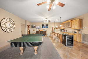 Game room featuring wine cooler, a ceiling fan, wet bar, and light tile patterned floors