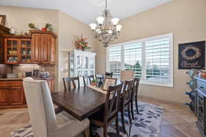 Dining space featuring suspended lighting, light tile patterned flooring, and vaulted ceiling