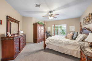 Carpeted bedroom featuring ceiling fan and a textured ceiling