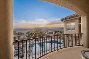 Balcony at dusk featuring view of pool and a residential view