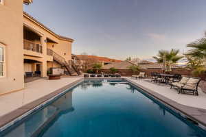 View of swimming pool with patio surround, a fenced backyard, outdoor dining area, and a balcony