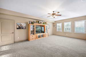 Unfurnished living room featuring carpet floors and ceiling fan