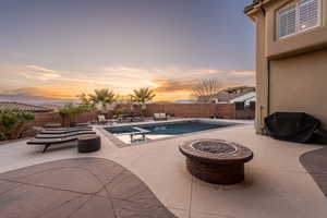 Relaxing pool / spa featuring a patio, a fenced backyard, and a fire pit