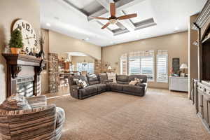 Living room with coffered ceiling, a fireplace, arched walkways, ceiling fan, and light tile patterned flooring