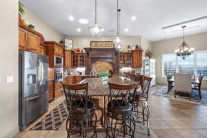 Kitchen featuring glass fronted cabinets, stainless steel appliances, a kitchen island with sink, wood finish cabinetry, and dark stone counters