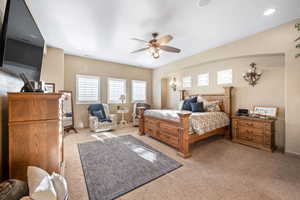 Bedroom featuring light colored carpet, ceiling fan, arched walkways, and recessed lighting