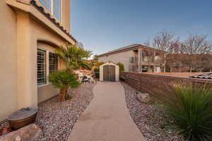 View of property exterior featuring a storage shed, stucco siding, and a fenced backyard