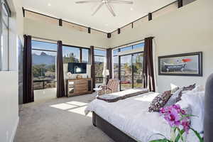 Bedroom with light carpet, a ceiling fan, and a high ceiling