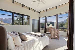 Bedroom with carpet floors, a high ceiling, and multiple windows