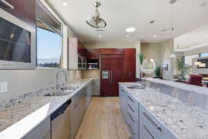 Kitchen featuring stainless steel appliances, light stone countertops, and plenty of natural light