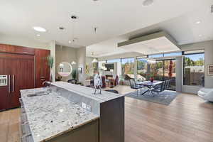 Kitchen with light wood finished floors, light stone countertops, open floor plan, and paneled refrigerator