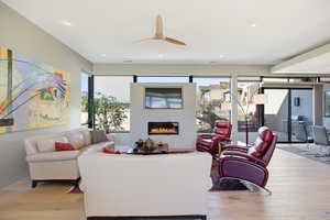 Living area featuring light wood-style floors, a glass covered fireplace, and recessed lighting