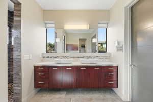 Bathroom with double vanity, backsplash, a walk in shower, and a walk in closet