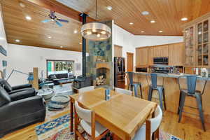 Dining space with a wood stove, a vaulted wood ceiling, ceiling fan, light wood-type flooring, and recessed lighting