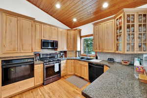 Kitchen with light wood finish cabinetry, black appliances, decorative backsplash, glass fronted cabinets, and recessed lighting