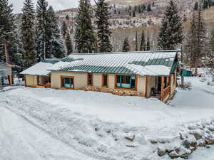 View of front of home with a standing seam roof, stone siding, and stucco siding