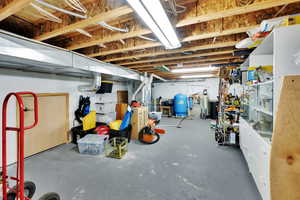 Unfinished below grade area featuring a water pressure tank and a water softener system