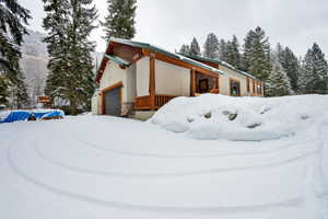 Snow covered property featuring stone siding and stucco siding