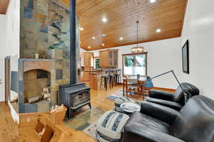 Living room featuring a wood stove, a vaulted wood ceiling, light wood-type flooring, and recessed lighting