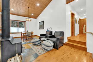 Living room with a wood stove, light wood finished floors, recessed lighting, and a vaulted wood ceiling