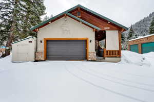 Contemporary home with stone siding, an outdoor structure, stucco siding, and a garage