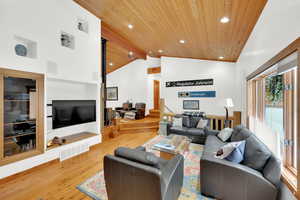 Living area featuring light wood-style flooring, a wood ceiling with exposed beams, and recessed lighting