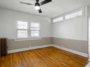 Spare room with radiator heating unit, light wood-type flooring, and a ceiling fan