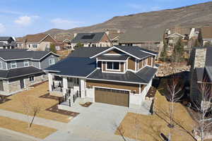 View of front of house featuring driveway, stone siding, a residential view, and a mountain view
