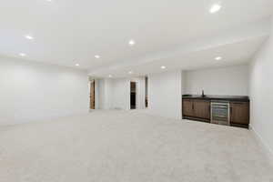 Basement with wine cooler, wet bar, light carpet, and recessed lighting