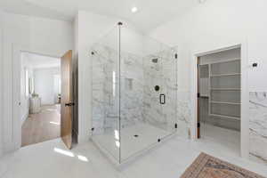Bathroom featuring a spacious closet, a marble finish shower, recessed lighting, and tile walls