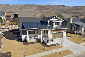 View of front of property featuring a standing seam roof, a porch, concrete driveway, an attached garage, and a mountain view