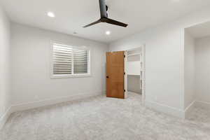 Unfurnished bedroom with a walk in closet, a ceiling fan, carpet, and recessed lighting