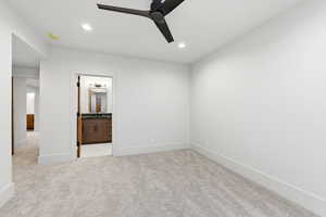 Unfurnished bedroom with light colored carpet, ceiling fan, ensuite bathroom, and recessed lighting