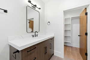 Bathroom featuring vanity, a spacious closet, and light wood-type flooring