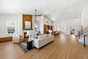 Living room with lofted ceiling, light wood-style floors, recessed lighting, a large fireplace, and ceiling fan